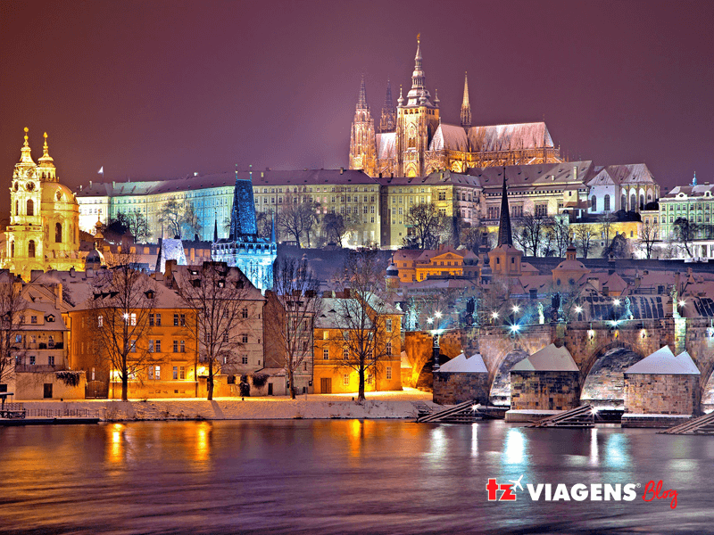 Um dos pontos turísticos de Praga mais importante, é o castelo de Praga. Na imagem noturna há o castelo centralizado bem iluminado, luzes azuis e amarelas colorem o castelo.