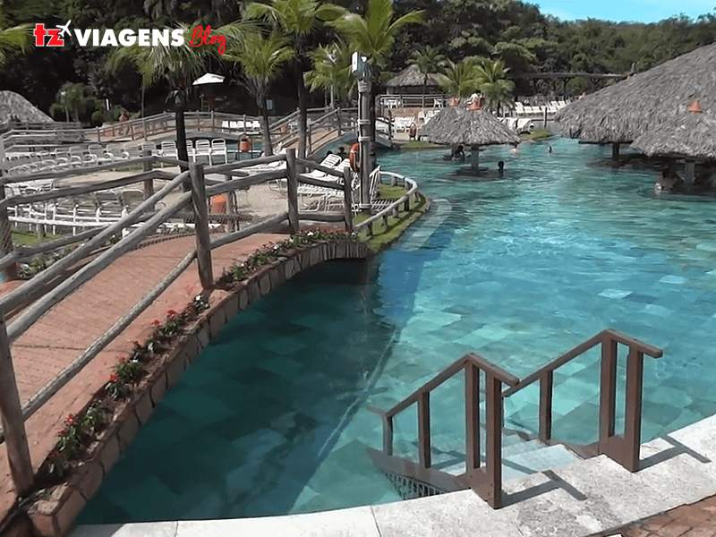 Caldas Novas é outro lugar para se visitar nas férias de julho. A imagem é de um resort, mostrando uma piscina com águas cristalinas e decks de madeira.