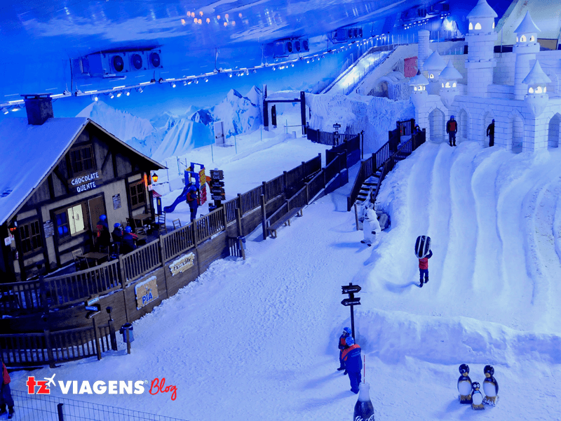 Lugar divertido para se visitar nas férias de Julho, Snowland, em Gramado. Imagem da estação de esqui artificial, com algumas pessoas andando e esquiando.