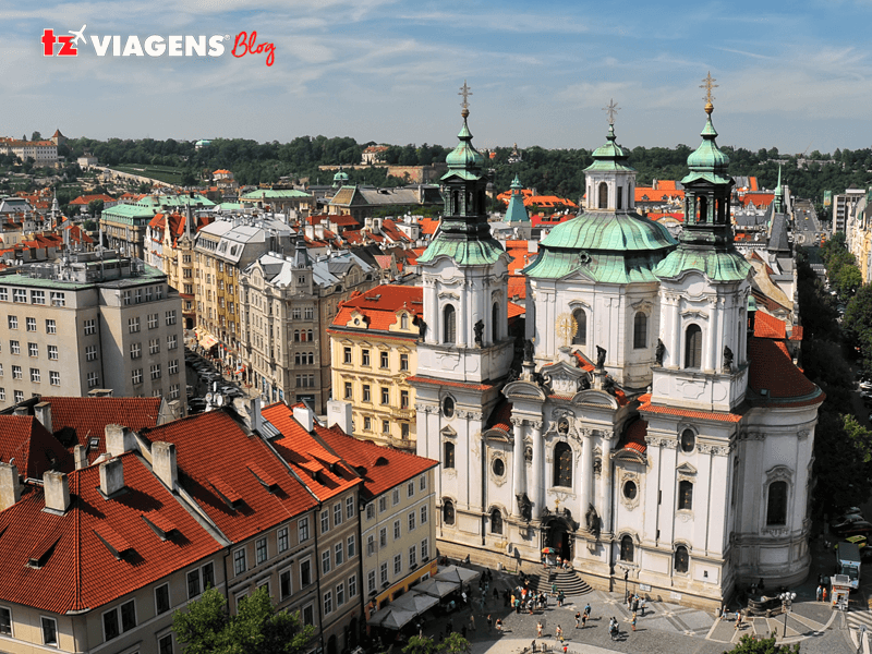Um pontos turístico de Praga para quem gosta de Igrejas é a São Nicolas. Na imagem aérea da igreja e outros prédios vizinhos, arquitetura antiga. A igreja posiciona-se ao canto direito da foto.