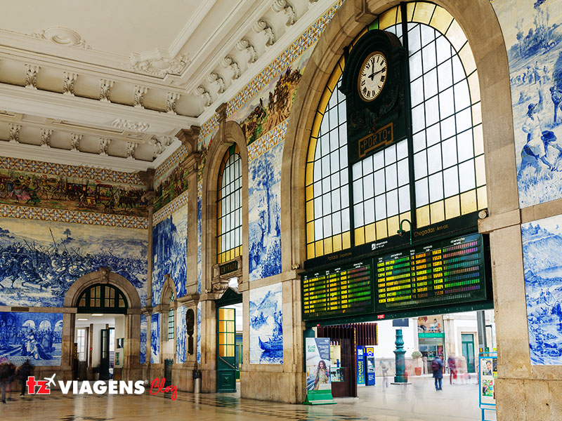 Estação de São Bento, Porto. É um ponto para conhecer em uma Viagem para Portugal. Foto interna da estação, tirada de baixo para cima e direita. Nas paredes os lindos azulejos e o relógio.