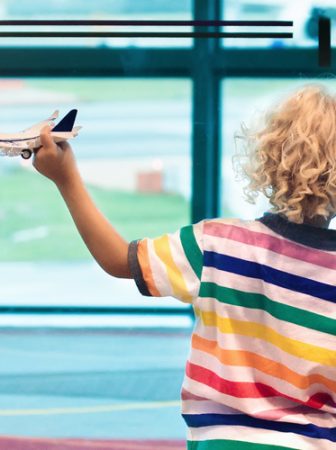 Imagem de duas crianças de costas em um aeroporto.Acompanha texto sobre os melhores destinos para viajar com crianças